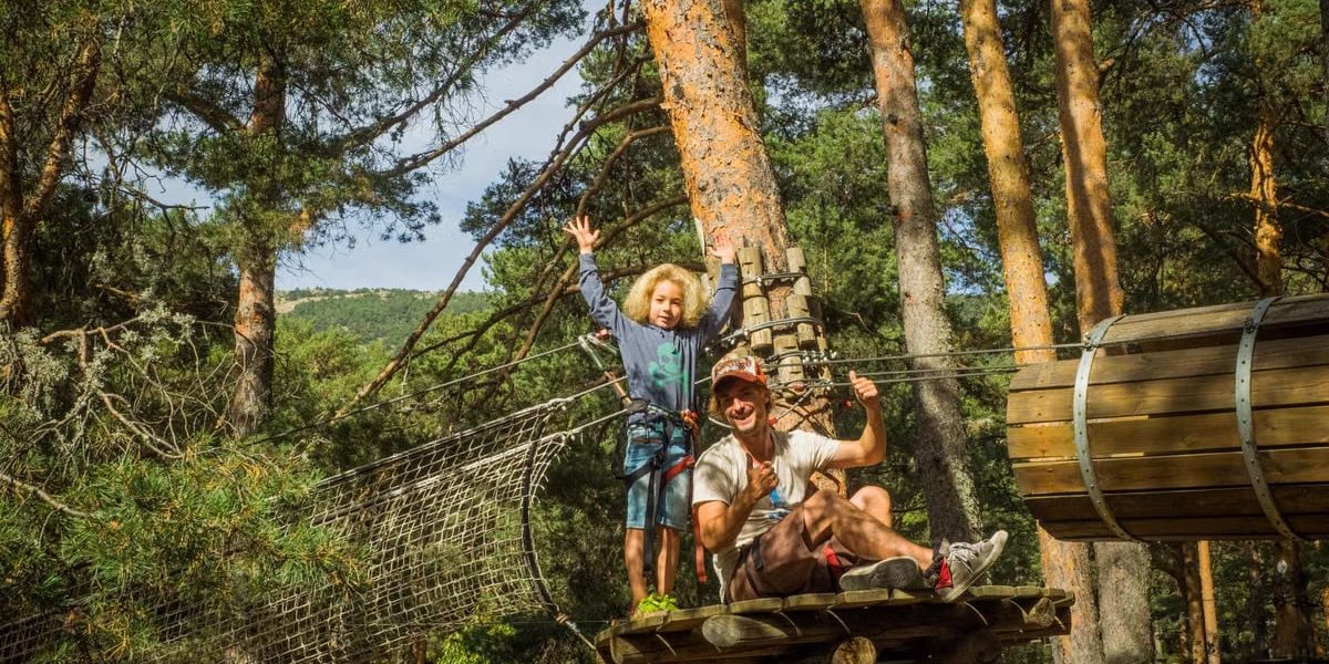 Father and child embrace adventure on a forest zipline in Cercedilla, Spain.