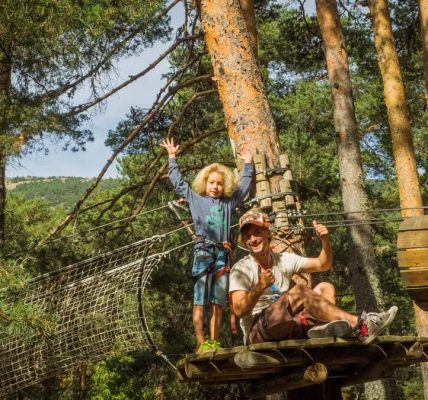 Father and child embrace adventure on a forest zipline in Cercedilla, Spain.