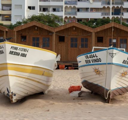 Colorful fishing boats resting on sandy Monte Gordo beach, Faro, Portugal.
